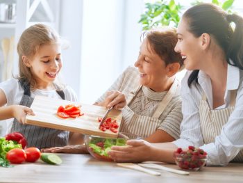 photo of grandmother, mother, and daughter preparing healthy foods together