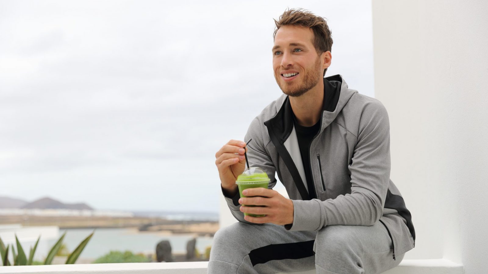 Photo of man sitting outside drinking green juice for a cleanse diet