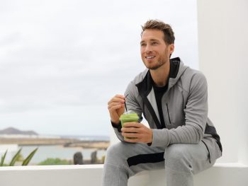 Photo of man sitting outside drinking green juice for a cleanse diet